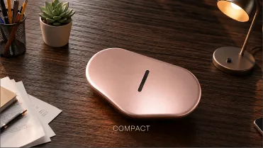 The device on a wooden desk beside a lamp and a plant.